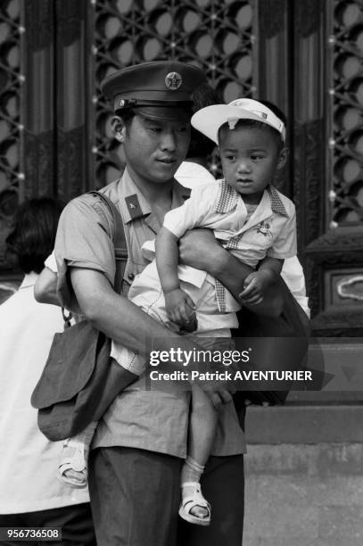 Un policier chinois porte son fils à Pékin en juijn 1987, Chine.