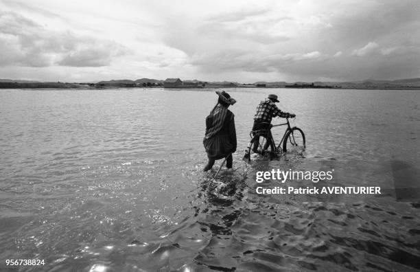 Un couple de péruvien en vélo lors des graves inondations près du lac Titicaca en mars 1986, Pérou.