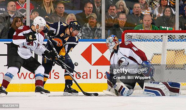 Derek Roy of the Buffalo Sabres tries to control the flying puck against John-Michael Liles and Craig Anderson of the Colorado Avalanche on January...