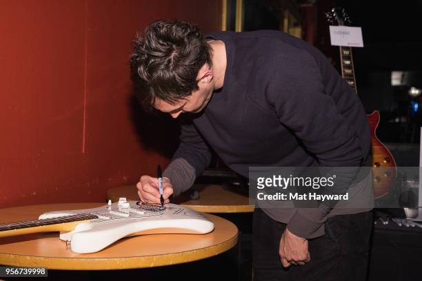 Guitarist Josh Klinghoffer of the Red Hot Chili Peppers signs an autograph after rehearsal for the Musicares Concert for Recovery at the Showbox on...