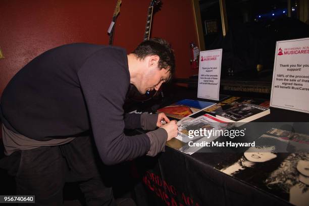 Guitarist Josh Klinghoffer of the Red Hot Chili Peppers signs an autograph after rehearsal for the Musicares Concert for Recovery at the Showbox on...