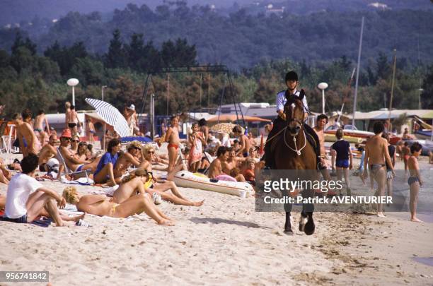 Femme policier à cheval sur une plage de Port Grimaud le 10 juillet 1984, France.
