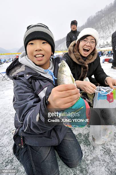 South Korean boy shows a trout caught through a hole created in a frozen river during a contest to catch trout in Hwacheon, 120 kilometers northeast...