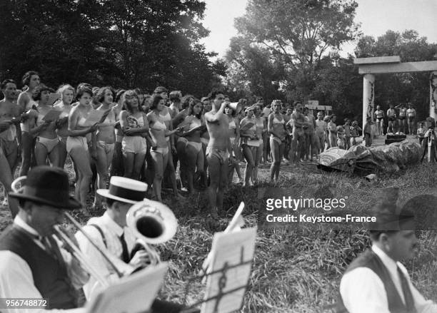 Jeunes gens à moitié dévêtus écoutent l'orchestre pendant la fête du naturisme au Domaine de Physiopolis à Villenes-sur-Seine, France en 1932.