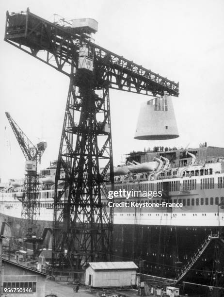 Une grue pose la cheminée du paquebot 'France' dans les chantiers navals le 1er juin 1959 à Saint-Nazaire, France.
