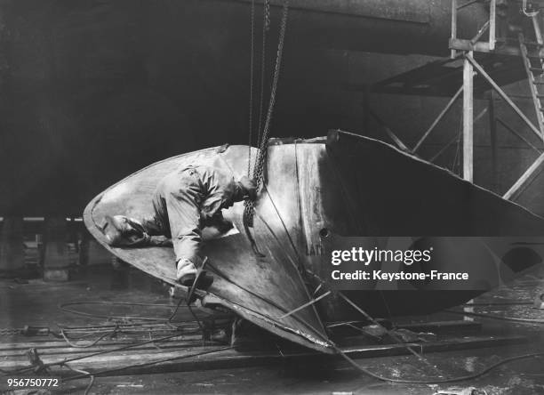 Ouvrier travaillant sur l'hélice du paquebot 'Normandie' en construction dans le chantier naval de Saint-Nazaire, France en 1935.