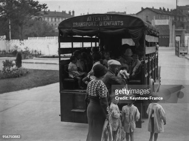 Des enfants montent dans un camion pour une sortie scolaire, à Pantin, France en août 1934.