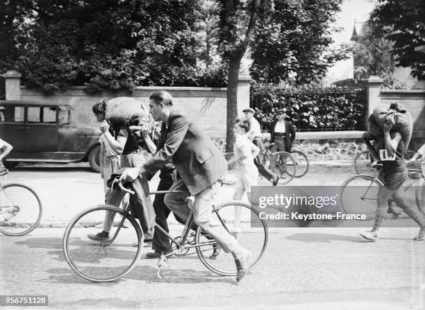 Course des charbonniers portant un sac d'anthracites sur le dos suivis par des cyclistes, à Nanterre, France en 1935.