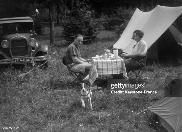 Des campeurs profitent des vacances pour déjeuner et se reposer avec leur chien en forêt de Marly, circa 1930 à Marly-le-Roi, France.