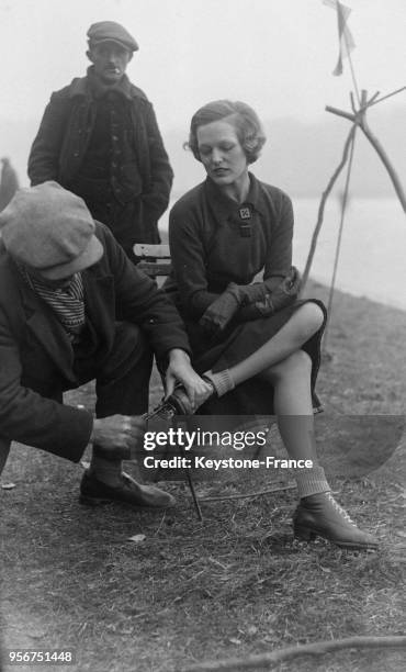 Un homme installe les lames aux patins de la femme, à Versailles, France en décembre 1933.