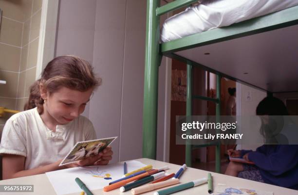 Petite fille lisant une carte postale lors d'une colonie de vacances du Comité Central d'Entreprise de la SNCF à Clairoix, en 2001, dans l'Oise,...