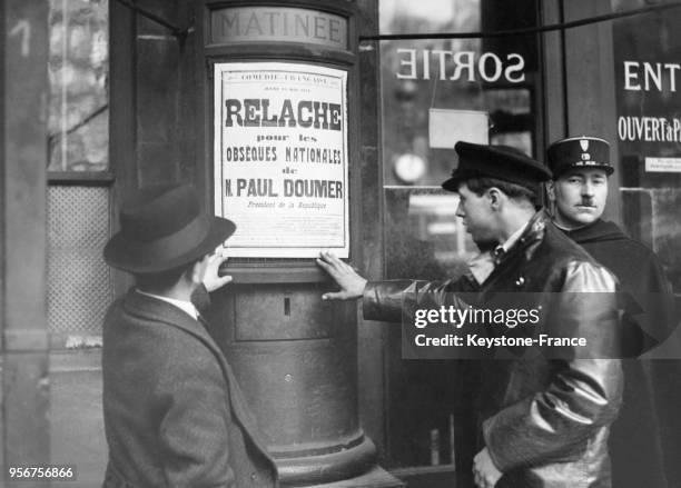 Deux hommes lisent l'affiche annonçant les obsèques de Paul Doumer dans une rue de Paris, France en mai 1932.