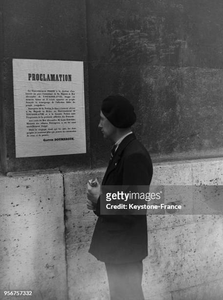 Un jeune homme lit la proclamation du gouvernement français rédigée après l'assassinat du Roi Alexandre 1er de Yougoslavie a Marseille et affichée...