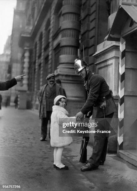 Une jeunee Parisiene présente ses voeux de bonne année à un pompier, à Paris, France en janvier 1933.