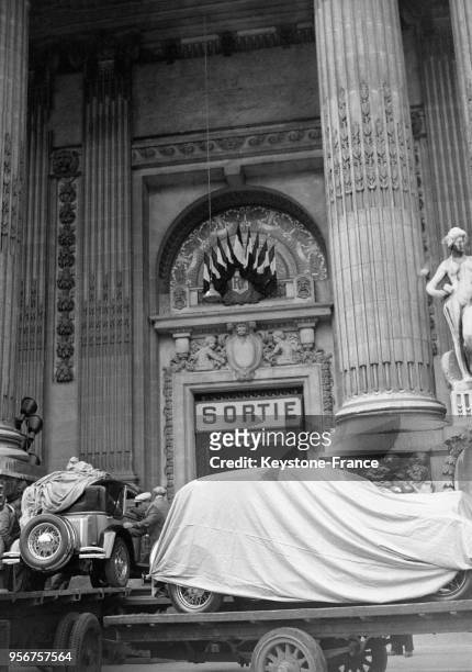 Arrivée d'un nouveau modèle de voiture caché sous une bâche, au Grand Palais à Paris, France en octobre 1932.