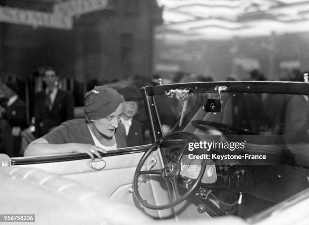 Une femme regarde attentivement l'intérieur d'une voiture présentée au 27e Salon international de l'auto à Paris, France en 1933.