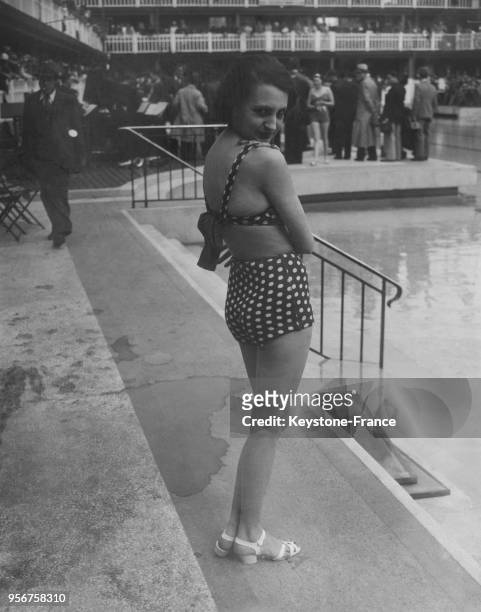 Une jeune femme présente un maillot de bain à la piscine Molitor à Paris, France en juin 1935.