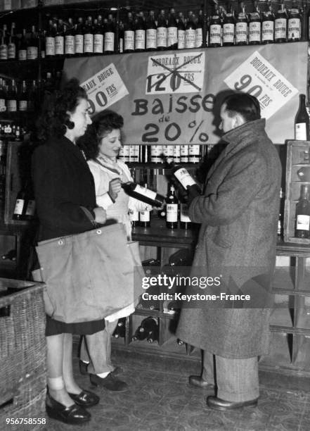 Dans une épicerie, un homme achètent du vin dont le prix a baissé, à Paris, France en 1946.