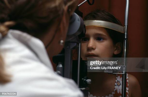 Ophtalmologue inspectant les yeux d'une petite fille à Paris, en 1995, France.