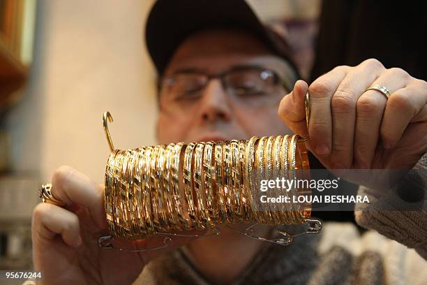 Syrian goldsmith shots clients traditional bracelets at his shop in the Gold Market at the historic bazaar of Old Damascus on January 6, 2010....