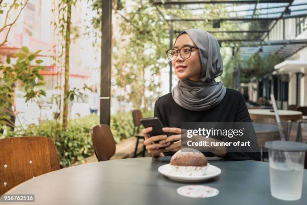 malay girl with hijab with her smartphone - malay culture stock pictures, royalty-free photos & images