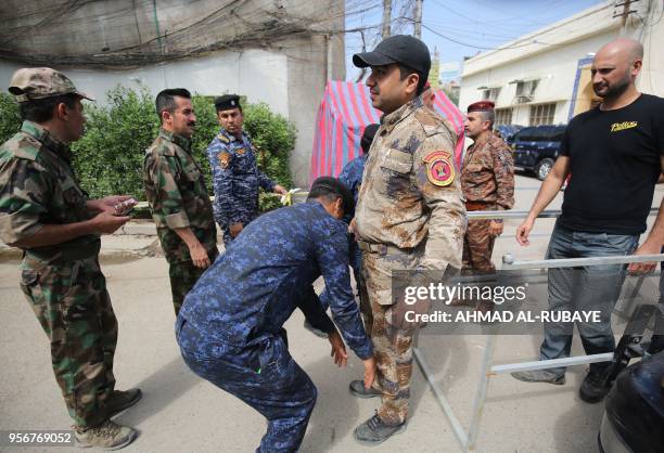 Member of the Iraqi security forces goes through security check before casting his vote at a polling station in the Iraqi capital Baghdad to vote...