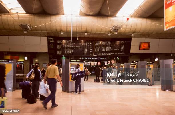 Tableau d'affichage des départs et guichet de billetterie automatique dans le hall de la gare de Montparnasse à Paris, France.