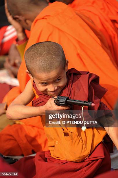 Young Buddhist monk plays with a toy gun during the fourth day of a teaching session led by Tibetan spiritual leader The Dalai Lama at The Kalachakra...