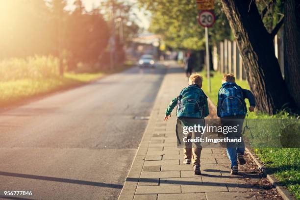 schule jungs zur schule laufen - backpack stock-fotos und bilder