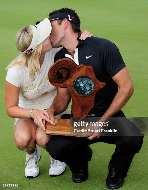 Charl Schwartzel of South Africa holds the winners trophy as he kisses his girlfriend Rosalind Jacobs after the final round of the Africa Open at the...