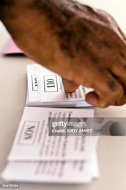 Man grabs ballots in the polling station of Cayenne on the French South American territory of Guiana, on January 10 for the referendum on the status...