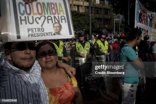 Supporters of Gustavo Petro, presidential candidate for the Progressivists Movement Party, hold up signs as police watch over a campaign rally in...