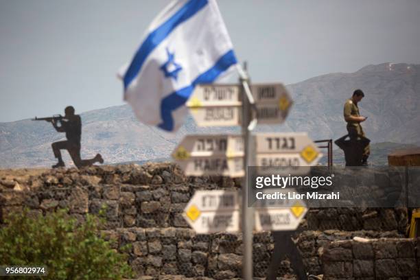 Israeli soldier is seen next to a signs pointing out distance to different cities on Mount Bental next to the Syrian border on May 10, 2018 in the...