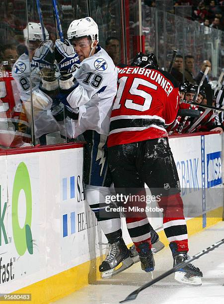 Stephane Veilleux of the Tampa Bay Lightning is checked along the boards by Jamie Langenbrunner of the New Jersey Devils during the continuation of...