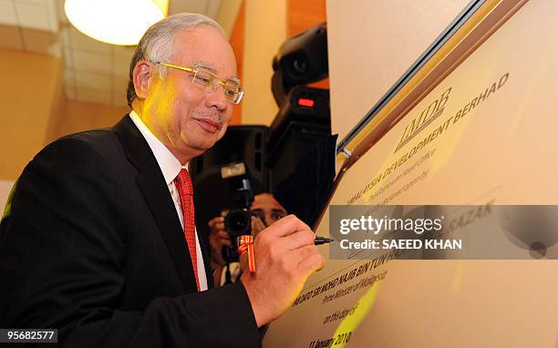 Malaysian Prime Minister Najib Razak signs a plaque after opening the head office of government development and investment firm 1Malaysia Development...