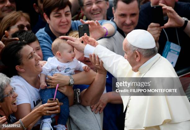 Pope Francis caresses the face of a baby during a pastoral visit in Loppiano, on May 10, 2018 near Grosseto, Tuscany.