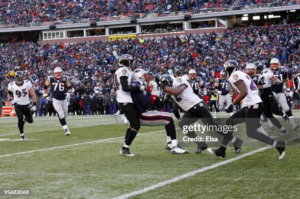 Randy Moss of the New England Patriots stopped after a reception by Ed Reed , Dominique Foxworth and Ray Lewis of the Baltimore Ravens during the...