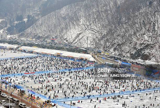 Thousands of anglers cast lines through holes created in the surface of a frozen river during a contest to catch trout in Hwacheon, 120 kilometers...
