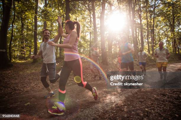 happy couple giving high-five while running marathon race in nature. - cross country running stock pictures, royalty-free photos & images
