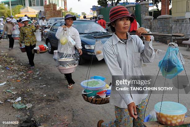 Cambodian women carry sweets along a street in Phnom Penh on January 11, 2010. Cambodia is one of 12 "hunger hotspot" countries, according to the...