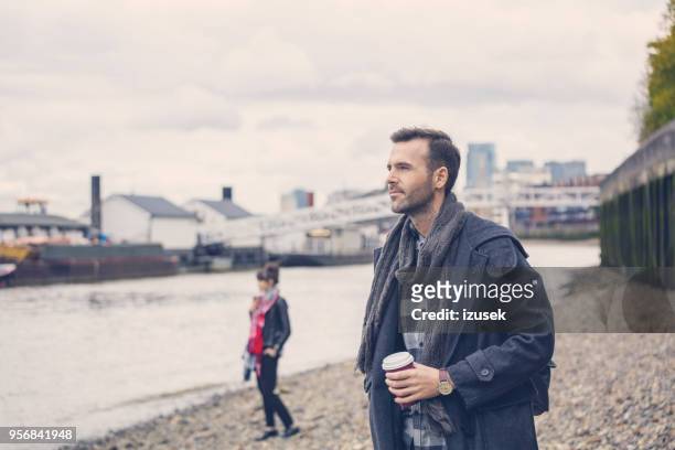 besorgt mann steht am ufer des flusses in der stadt - city von london stock-fotos und bilder