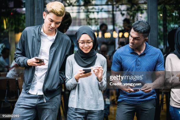 giovani asiatici che usano gli smartphone - malese foto e immagini stock