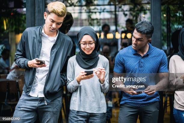 young asian people using smartphones - islam religion stock pictures, royalty-free photos & images