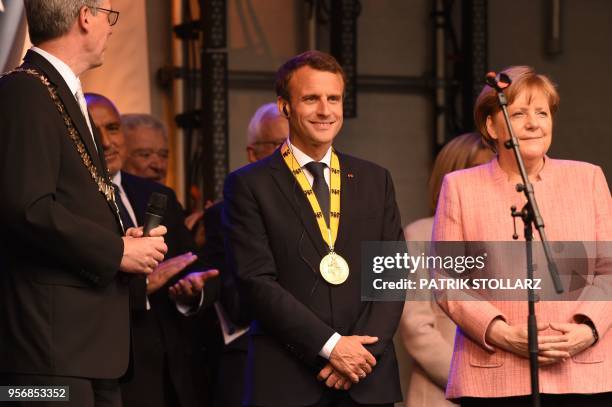 France's President Emmanuel Macron stands next to Germany's Chancellor Angela Merkel at the end of the Charlemagne prize award ceremony on May 10,...