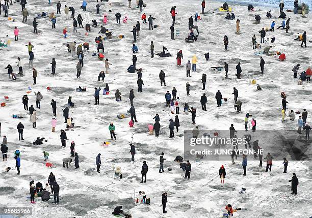 Thousands of anglers cast lines through holes created in the surface of a frozen river during a contest to catch trout in Hwacheon, 120 kilometers...