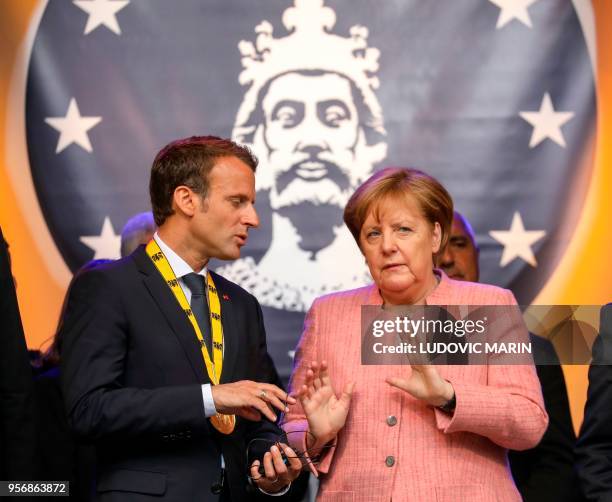 France's President Emmanuel Macron and German Chancellor Angela Merkel confer at the end of the Charlemagne prize award ceremony on May 10, 2018 in...