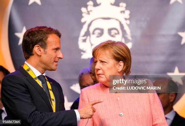 France's President Emmanuel Macron and German Chancellor Angela Merkel confer at the end of the Charlemagne prize award ceremony on May 10, 2018 in...