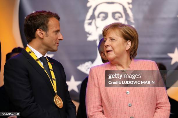 France's President Emmanuel Macron stands next to German Chancellor Angela Merkel at the end of the Charlemagne prize award ceremony on May 10, 2018...