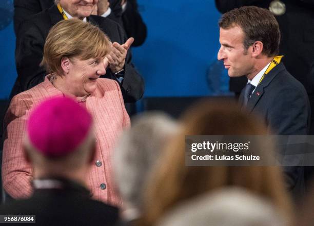 French President Emmanuel Macron and Angela Merkel react after Macron receives the International Charlemagne Prize on May 10, 2018 in Aachen,...
