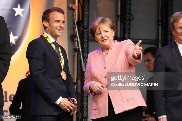 France's President Emmanuel Macron and German Chancellor Angela Merkel confer at the end of the Charlemagne prize award ceremony on May 10, 2018 in...